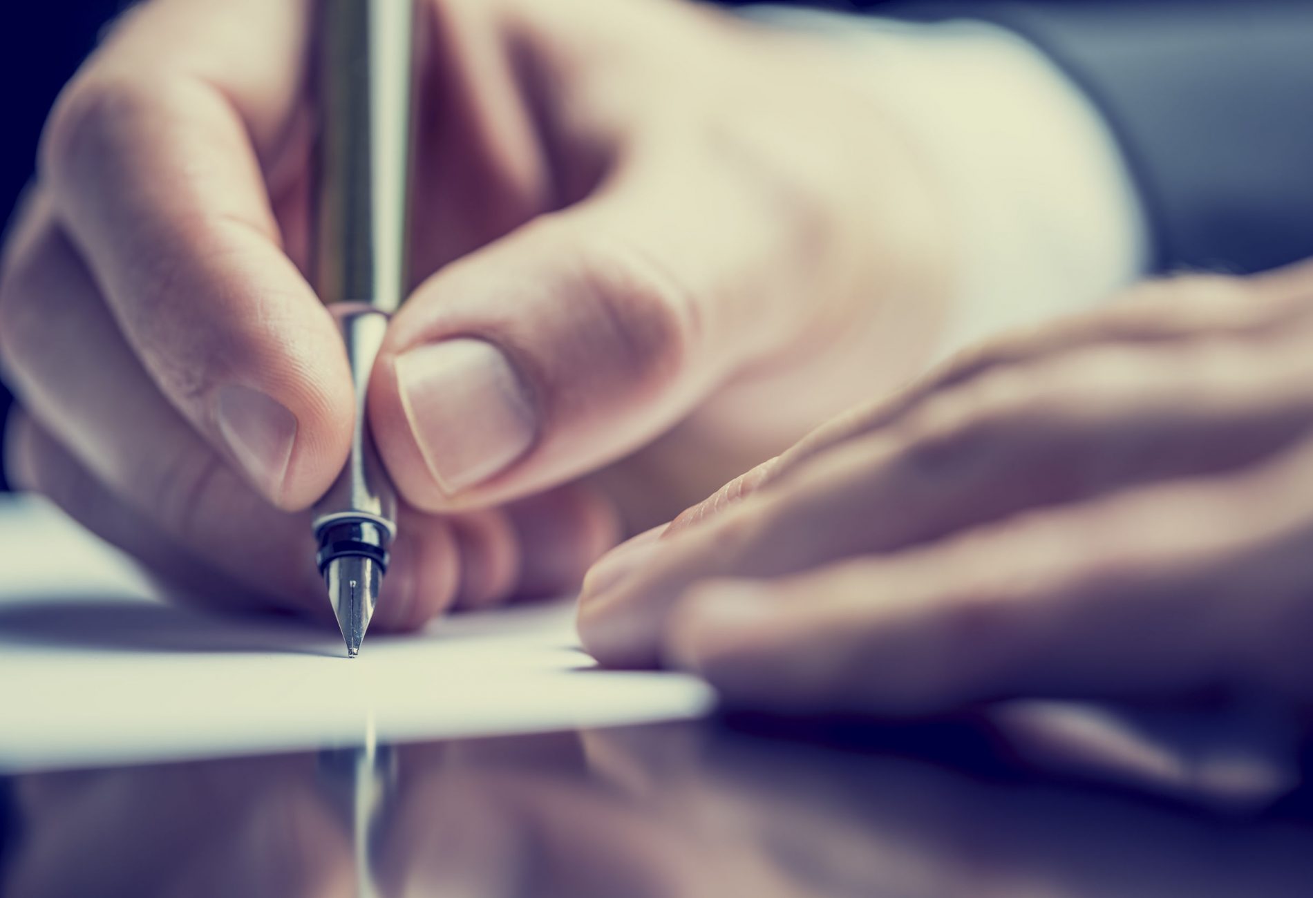 Retro effect faded and toned image of a man writing a note with a fountain pen.