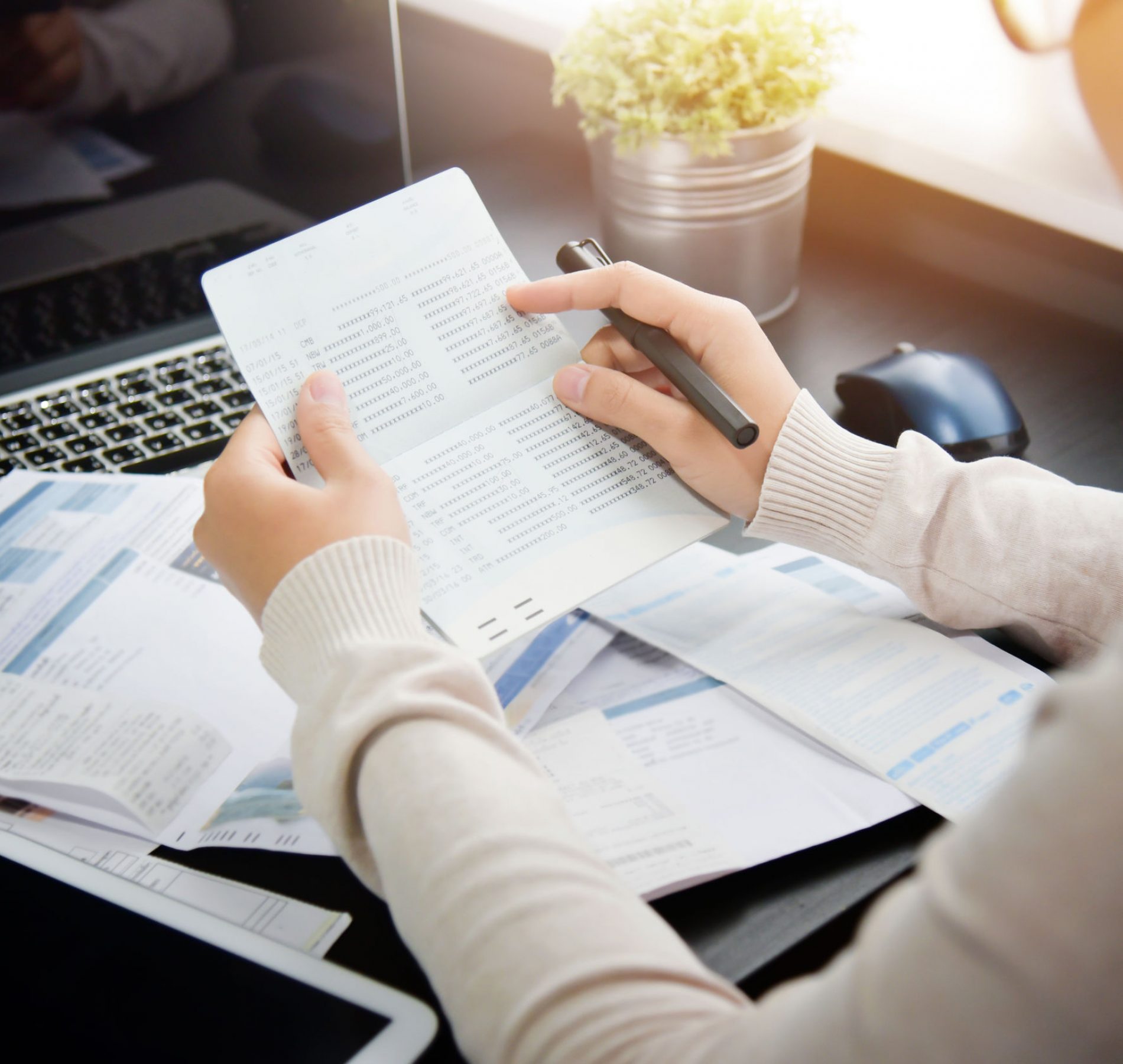 Asian woman looking to saving account book and calculating her monthly expenses with calculator. Debt.